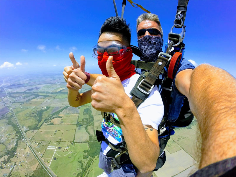 A tandem skydiver gives two thumbs up.