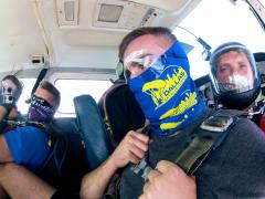 A group of skydivers sit in the cabin of the plane.