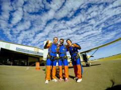 Three skydivers pose for the camera.