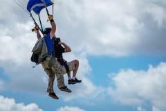 A skydiver in shorts gets ready to land.