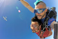 Tandem skydivers with the plane off in the distance.