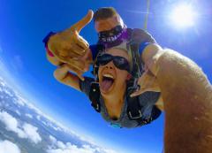 An energetic woman poses for the camera while skydiving.