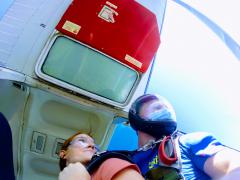 Two jumpers look out the cabin door as they prepare to skydive.