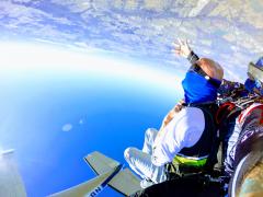 Tandem jumpers free fall upside down with plane overhead.