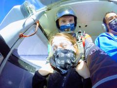 A young women looks at the ground as she prepares to skydive.