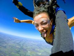 A young woman poses for the camera while skydiving.