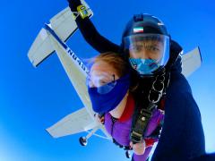 Two skydivers and the plane they just jumped from overhead.